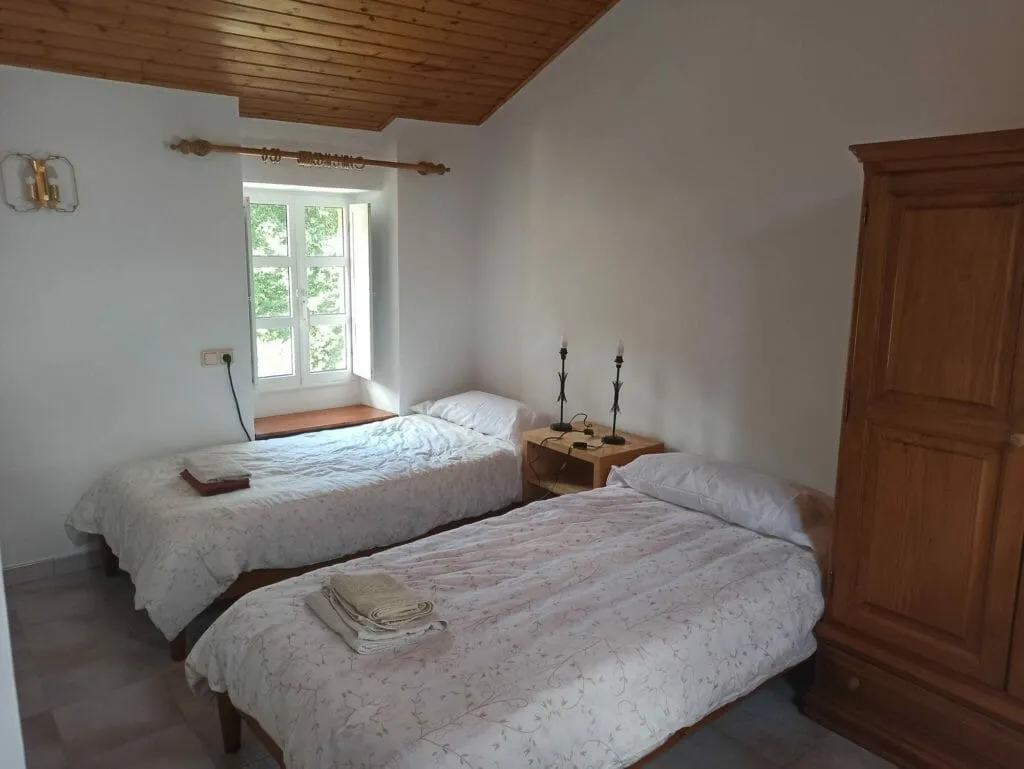 A habitación 104 antes do seu redeseño: dúas camas individuais con colchas de flores, un armario de madeira e teito de madeira