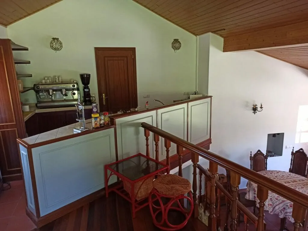 O café antes do seu redeseño: paneis verde claro, madeira escura e unha mesa de ratán vermella xunto á cafeteira