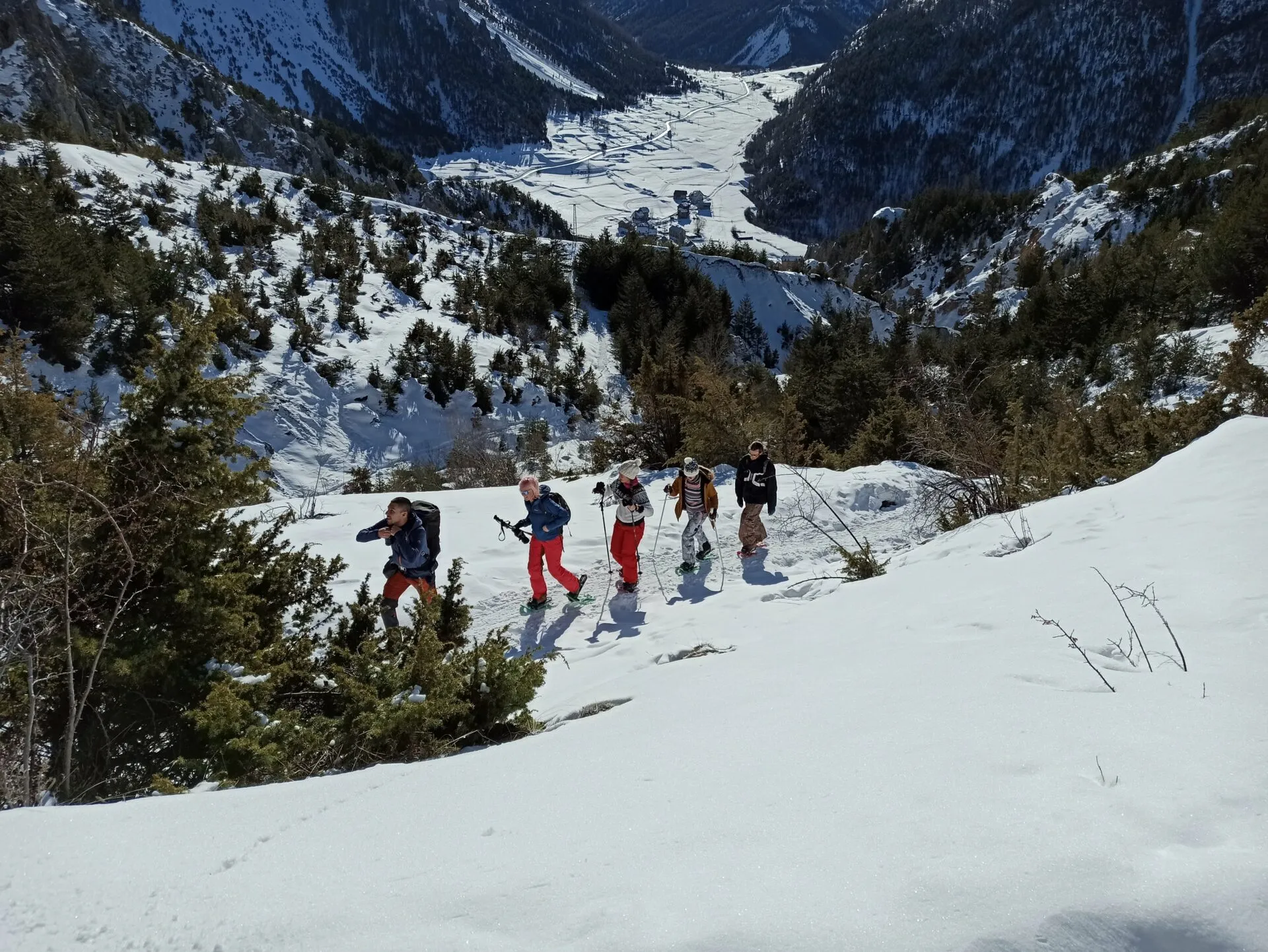 Cinco persoas con raquetas de neve nunha ladeira nevada sobre un val alpino, en Cloud Citadel