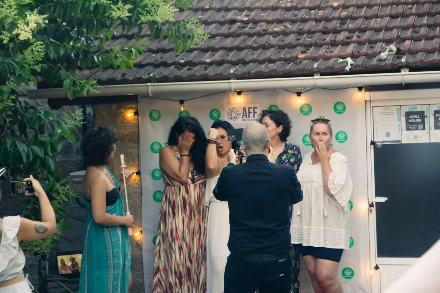 Varias persoas tapan a cara sorprendidas diante dun photocall do AFF Anceu Film Festival mentres un home as fotografía