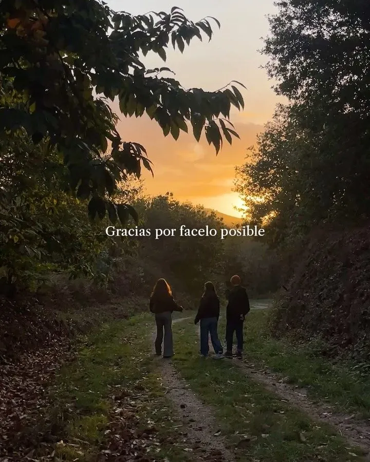 Three people seen from behind walking along a grassy track between trees at sunset; overlaid text reads “Gracias por facelo posible”