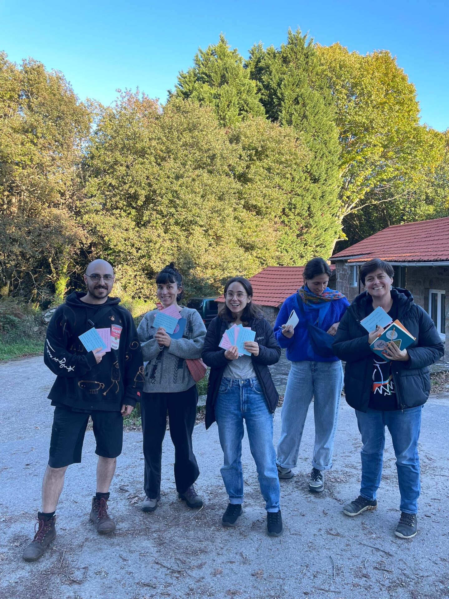 A group of people standing together outdoors in the Galician countryside, holding papers during a community gathering
